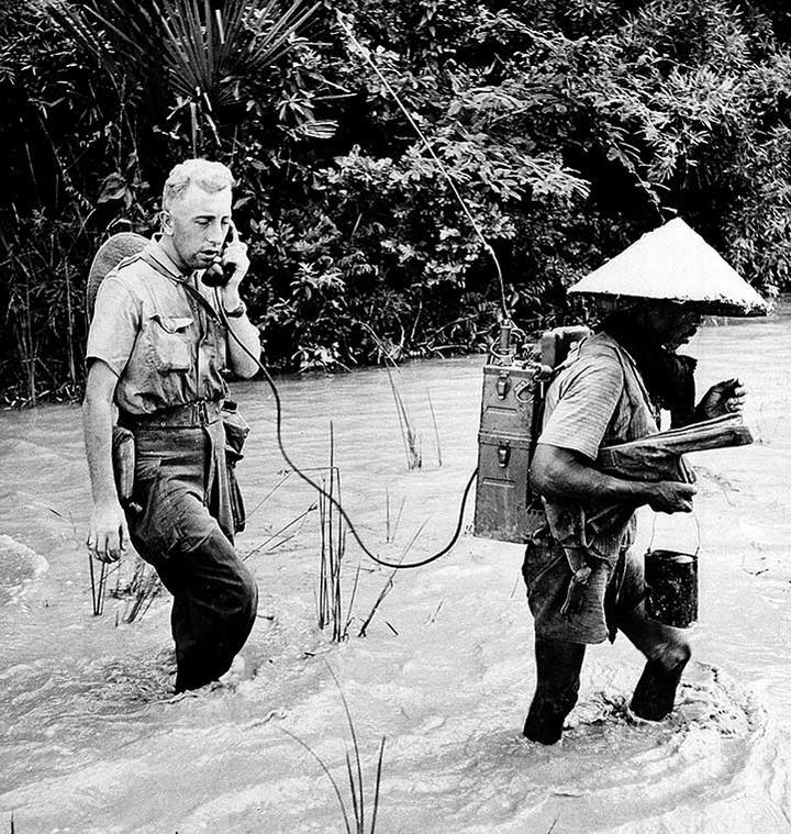 A native soldier of the French-Indochinese Union army carries a portable radio set strapped to his back, while Sgt.-Major Poncelet of Ecouviez, France, is signaling his position to the unit commander, during war operations in Viet Minh-held territory, some 25 miles northeast of Saigon, in southern Vietnam.